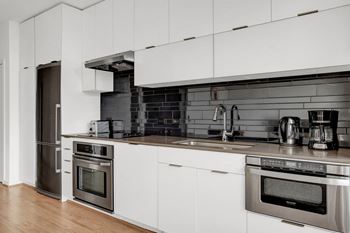 a kitchen with white cabinets and stainless steel appliances at The Shay, Washington, 20001
